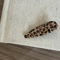 Dettaglio del fermaglio per capelli leopardato a goccia su una superficie minimalista - Fermaglio a Goccia Leopardato