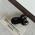 Detailed macro view of the glossy dark brown acetate bow hair clip with gold logo - Khaki Bow Black Hair Clip