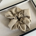 Elegant khaki pleated fabric scrunchie with a matte silk texture on a beige tray - Milk Tea