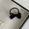 Elegante elastico per capelli con fiocco in velluto nero su sfondo beige dal design pulito - Fiocco per Capelli Nero
