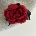 Gros plan d'une pince à cheveux en fleur crochetée rouge avec des pétales tricotés - Pince à Cheveux Fleur Rouge