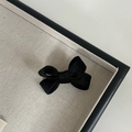 Dettaglio di un fermaglio per capelli con fiocco in velluto nero su vassoio beige - Molletta con Fiocco Nero