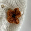 Makroaufnahme der handgefertigten Häkelblume in Vintage-Karamell und Dunkelgrün - Orange