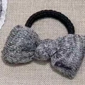 Detalle de coletero de lazo tejido gris con texto bordado sobre fondo de arpillera rugosa - 1# Goma para el Pelo con Lazo de Punto Gris