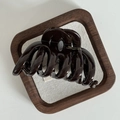 Dettaglio macro della molletta marrone cioccolato lucida con logo dorato su vassoio - Bar Shape Style