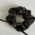 Détail macro du chouchou léopard avec perle décorative et cordon en cuir noir fin - Élastique Coeur Léopard (2# Léopard Café Élastique Coeur Léopard)