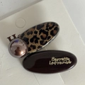 Detalle de pinzas ovaladas de leopardo y marrón oscuro con letras doradas en cartón - Par de Pinzas Ovaladas Marrón Leopardo
