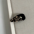 Detail of velvet leopard print bow hair clip with golden metallic brand logo plate - Leopard Black Stitching Triangle Hair Clip