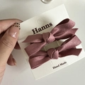 Détail de deux barrettes à nœuds en satin rose poudré sur une carte de présentation - Style Nœud Rose Coréen Satin