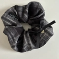 Detail eines grauen Karo-Scrunchie mit schwarzer Seidenschleife und Herzanhänger - Schwarz Streifen Haargummi Schleife