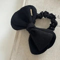 Dettaglio dell'elastico per capelli a fiocco in lana con perle e targhetta dorata - Nero