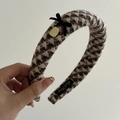 Detailaufnahme des braunen Stoff Stirnbands mit Hahnentritt Muster und kleiner Samtschleife - Dreieckiges Karomuster-Stil
