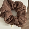 Detail view of brown knitted scrunchie with soft ribbed texture and side logo tag - Khaki Striped Scrunchie