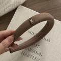 Detailed close-up of a brown tweed headband with an elegant vintage bow emblem plate - Khaki Oval Bow