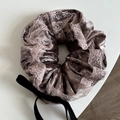 Detail van taupe fluwelen scrunchie met roze kant en een lange zwarte strik - Paarse Scrunchie Met Strik