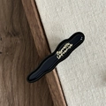 Close-up of black wavy acetate hair clip with gold Barrette La France lettering - Blue Wavy Clip with Gold Label
