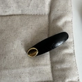 Detail of a black leather oval hair clip featuring a gold metal PARIS engraved plate - Black Curved Gold Label