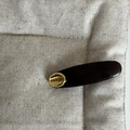 Deep brown leather hair clip with gold Paris metal inlay on beige fabric background - Khaki Curved Gold Label