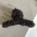 Dettaglio di un mollettone in peluche grigio antracite su uno sfondo di libro elegante - Grigio