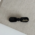 Detail van zwarte glanzende strik haarclip met gouden Barrette La France tekst details - Zwarte Strikstijl