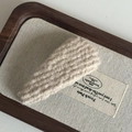 Detail van crème kabelgebreide haarclip met textuur en weefpatroon op linnen tray - Gebroken Wit Gestreept