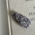 Close-up of a grey plush tweed hair clip on a minimalist fabric book background - Gray Plush Hair Clip