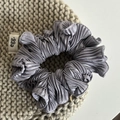 Detail van de grijze geplooide haarelastiek met satijnglans op beige gebreide achtergrond - Blauw