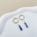 Détail de boucles d'oreilles dorées avec résine marbre bleu et cube sur plateau blanc - Style Marbre Bleu Encre (TL-E0100-02-lnkblue)