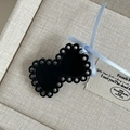 Detail of a black cutout bow hair clip with a light blue ribbon on a jewelry box - Black