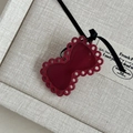 Detailed view of a dark red bow accessory with hollow cutouts and a thin black ribbon - Burgundy