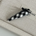 Close-up of black and white plaid hair clip with a delicate black ribbon bow detail - Black White Grid Triangle Fabric with Black Bow