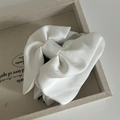 Close-up of a large white satin bow hair claw clip with elegant silky texture on a tray - White