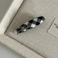 Close-up of gingham hair clip with silver handmade metal script on linen tray - Black White Grid Oval with Handmade Metal Letter