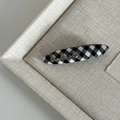 Detail view of British style gingham hair clip with a gold handmade metal logo - Medium Black White Grid Oval with Handmade Metal Letter