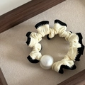 Detailweergave van de crèmekleurige scrunchie met zwarte ruches en een witte parelmoer kraal - Crèmewit (4# Zwarte Rand Wit Parel Haartouw)