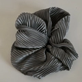 Gros plan sur un chouchou en tissu plissé gris foncé avec texture ondulée et fini satiné - Gris
