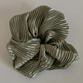 Détail d'un chouchou vert sauge en tissu plissé avec un effet de brillance métallique - Vert
