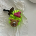 Macro-opname van een groene spiraal haarelastiek met bruine beer en roze letter hanger - Groen (A)