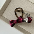 Detailed macro view of pink checkered bow hair clip with silver heart on beige fabric - Rose Red Black Plaid Bowknot Claw Clip