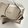 Detail of a French-style khaki layered bow on a black slim headband, top view - Coffee