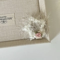 Detail of a white fluffy knit scrunchie with a delicate pink fabric rose flower accent - White Plush Star Hair Clip