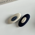 Detail view of oval fabric-wrapped hair clips in beige and navy blue with brand logo - Oval Navy And Beige Tweed Style