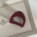 Detail view of the burgundy pumpkin hair claw with polished finish on beige fabric - Wine Red Oval Shape