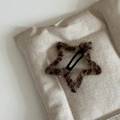 Close-up of star-shaped plush hair clip with leopard print pattern on beige fabric - Dark Leopard Star