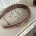 Détail d'un chouchou marron texturé avec plaque dorée posé sur des livres anciens - 1# Serre-tête Café avec Étiquette Dorée