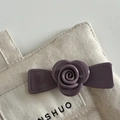 Dettaglio di un fermaglio per capelli a rosa viola in acetato su una borsa di tela neutra - Viola