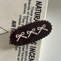 Macro view of brown acrylic hair clip with pink bow patterns and wavy edges - Brown Three Pink Bows Style