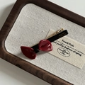 Close-up of a glossy red acetate bow barrette with gold metal clip on linen display - Wine Red Bow Duckbill Clip