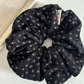 Primo piano dell'elastico in velluto a coste nero con fiori e etichetta JOY - Nero Floreale