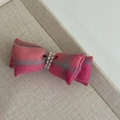 Detailed view of pink plaid bow hair clip with decorative pearls on beige fabric tray - Pink Bow Rhinestone Hair Clip